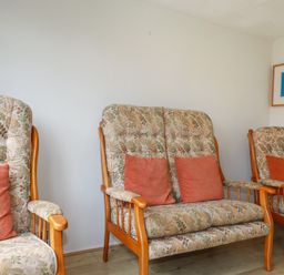A sitting area with floral upholstered wooden chairs and a framed abstract artwork on the wall at Constantine Bay near St Merryn