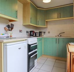 A kitchen with green cabinets white appliances and cooking utensils at Constantine Bay near St Merryn