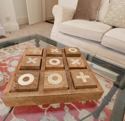 A wooden tic tac toe game on a glass coffee table with a patterned rug and a white sofa with cushions in the background at Flat 1 in Scarborough