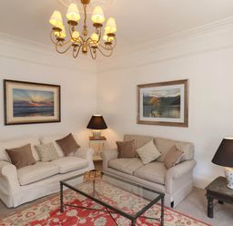 A living room with two sofas a glass coffee table two table lamps and framed pictures on walls at Flat 1 in Scarborough