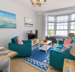 A living room with teal sofas a coffee table a television and large windows at Two @ No36 in Weymouth