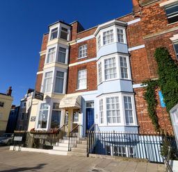 A brick building with bay windows and signs for Bay View Hotel on a street with parked cars