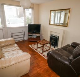A living room with two sofas a small table a television on a stand a fireplace and a large mirror at Freshwater East in Freshwater East