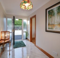 A hallway with a side table and lamp a green mat and a framed painting at Nelly's House in Gortahork County Donegal