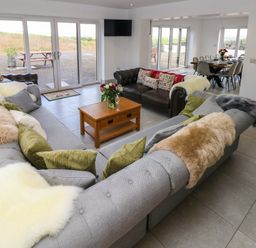 A living room with sofas pillows and a wooden coffee table connected to a dining area at Little Pale Near Whitland