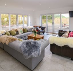A sitting room with sofas, a coffee table, and large windows at Little Pale Near Whitland