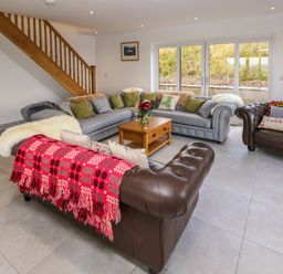 A living room with sofas pillows a wooden coffee table and a staircase at Little Pale Near Whitland