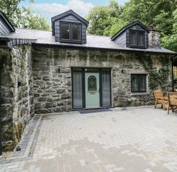 A house with a stone wall and patio area at Frongoch Old Power House in Dolgellau