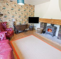 A living room with red leather armchairs a wooden table fireplace and a wall-mounted TV at Clearbrook Lodge Llanarthney nr Llandeilo Carmarthenshire