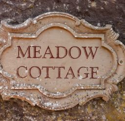 A decorative plaque with the words Meadow Cottage on a stone wall at Meadow Cottage in Llanarthney nr Llandeilo Carmarthenshire