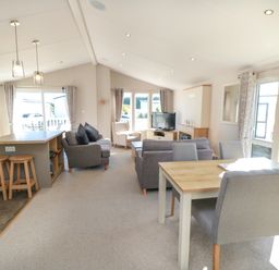 An open plan living room and kitchen with sofas dining table stools and a television at 28 Finch in Cayton Bay