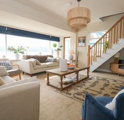 A living room with sofas a wooden coffee table and stairs near a television at Swn Y Wylan Red Wharf Bay near Benllech