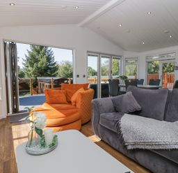 A living room with orange and gray sofas and a white coffee table at Lakeland View Ambleside 86 White Cross Bay near Windermere