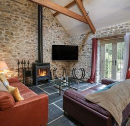 A living room with a sofa, coffee table, and fireplace at St Dogwells Barn near Wolfscastle