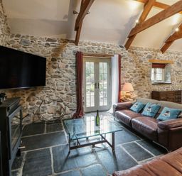 A living room with a television and a leather sofa at St Dogwells Barn near Wolfscastle