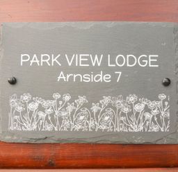 A sign on a wooden wall that reads Park View Lodge Arnside 7 with a floral design at the bottom Park View Lodge Arnside 7 South Lakeland Leisure Village near Carnforth