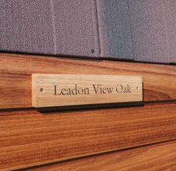 A wooden sign with the text Leadon View Oak mounted on a wooden wall