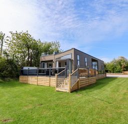 An outdoor view of a house with a deck and grass at The Lodge @ Racecourse House Babell near Holywell