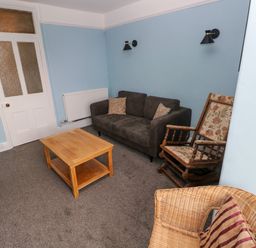A living room with a grey sofa wooden coffee table rocking chair and wicker chair at Rushfield in St Dogmaels North Pembrokeshire
