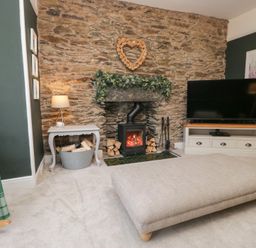 A living room with a stone wall and fireplace at The Wonky Nest in Bowness-On-Windermere