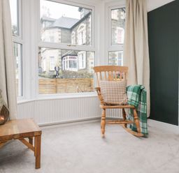 A living room with a rocking chair and a wooden table at The Wonky Nest Bowness-On-Windermere