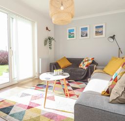 A living room with two sofas a small white coffee table and framed pictures on the wall at Beachcomber in Maer near Bude