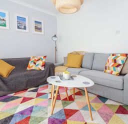A living room with two sofas and a colorful triangular patterned rug at Beachcomber in Maer near Bude