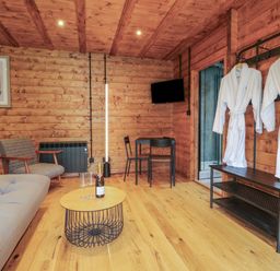 A wooden room with sofa chair coat rack and table with glasses and bottle at Badgers Burrow in South Luffenham near Edith Weston