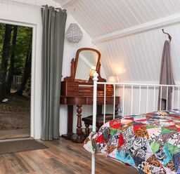 A bedroom with a metal bed frame and a colorful patchwork quilt and a wooden dressing table with a mirror and a lamp at Ballybeg Pod 9 Ballybeg near Tinahely County Wicklow