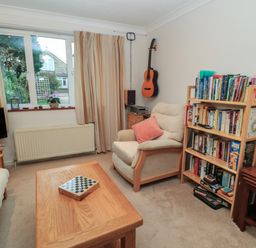 A living room with an armchair, bookshelf, guitar on the wall, coffee table, television, and window at Old Harry Cottage 16 in Swanage