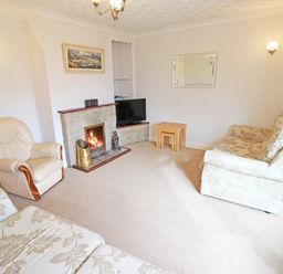 A living room with a sofa armchair fireplace television and nested tables at Artists Cottage in Minffordd near Penrhyndeudraeth