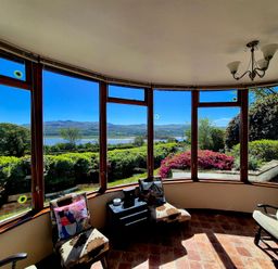 A conservatory with chairs and table overlooking a view at Artist's Cottage in Minffordd near Penrhyndeudraeth