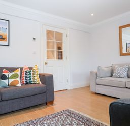 A living room with two sofas with cushions a wall mirror a glass door and a framed picture at 6 Willows Green in Aldeburgh