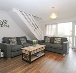 A living room with two sofas and a coffee table under stairs at 102 Waterside Park in Corton