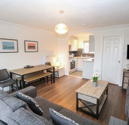 A living room with sofa coffee table dining table and an open kitchen at 102 Waterside Park in Corton