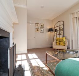 A living room with a fireplace armchair floor lamp glass coffee table and window at Holm Oak Lodge in Tendring near Weeley