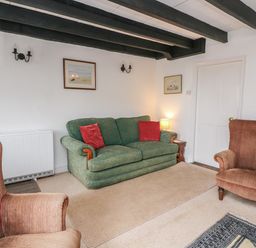 A living room with two armchairs and a sofa with cushions at Vine Cottage in East Prawle