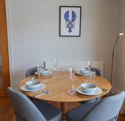A dining room with a round table set for meals at 22 Dart Marina in Dartmouth