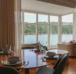 A dining room with a table set for meals and a view of the marina at 22 Dart Marina Dartmouth