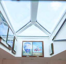 A skylight ceiling with framed pictures of a hot air balloon and a gyrocopter on the walls at Howard Cottage in North Littleton near Offenham