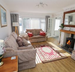 A living room with sofas a fireplace a rug and a large mirror at Howard Cottage in North Littleton near Offenham