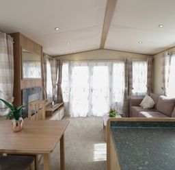 A living room with a sofa a table with a plant and large windows with curtains at Elm in Denny