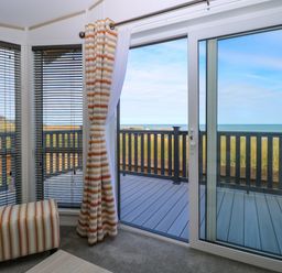A room with sliding glass doors leading to a deck with a sea view at Seaview Lodge in Bacton