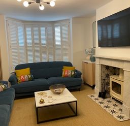 A living room with blue sofas and a marble coffee table in front of a fireplace with a mounted TV at Happy Place in Sheringham