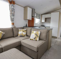 A living room with a sofa and kitchen area at Ash in Denny