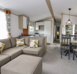 A living room with a sofa and kitchen area at Ash in Denny