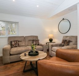 A sitting area with a sofa armchair wooden coffee table lamp and round mirror at Esk Pike 9 Skiptory Howe White Cross Bay near Windermere