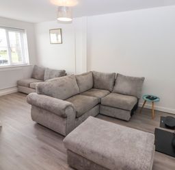 A living room with grey sofas a window small round table and a wall mounted television at 69 Ffordd Y Meillion in Llanelli