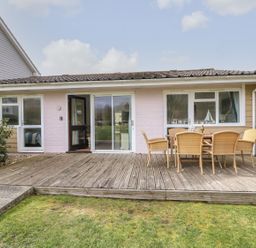 A wooden deck with a table and six chairs outside a single story house at Forbes C1 in Yarmouth