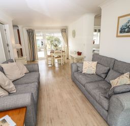 A living room with two grey sofas and a dining area with white chairs at Forbes C1 in Yarmouth